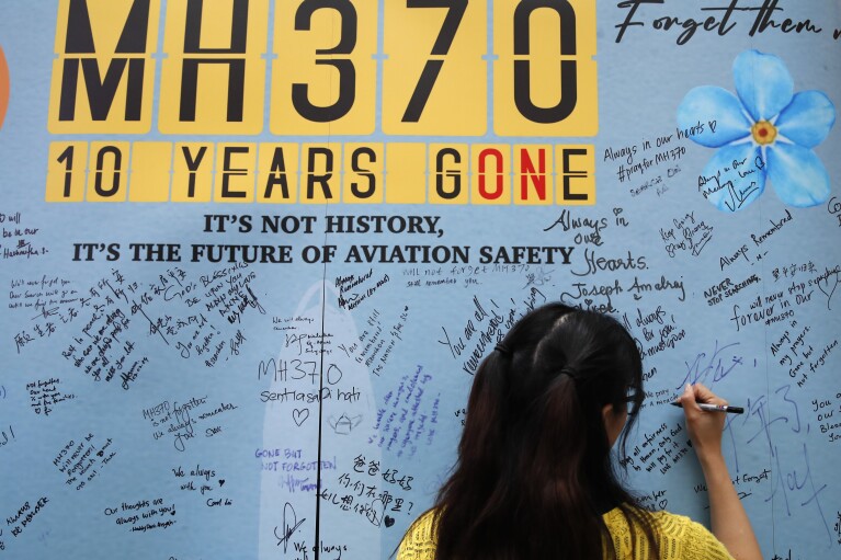 A woman writes well messages on a message board during the tenth annual remembrance event at a shopping mall, in Subang Jaya, on the outskirts of Kuala Lumpur, Malaysia, Sunday, March 3, 2024. Ten years ago, a Malaysia Airlines Flight 370, had disappeared March 8, 2014 while en route from Kuala Lumpur to Beijing with over 200 people on board. (AP Photo/FL Wong)