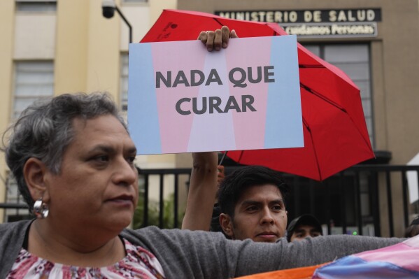 Un manifestante de la comunidad LGBTI+ con un cartel a favor de las personas trans en una protesta contra un decreto del gobierno de Perú que clasifica siente identidades de género como enfermedades mentales, en Lima, Perú, el viernes 17 de mayo de 2024. (AP Foto/Martín Mejía)