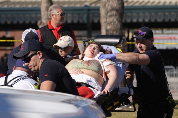 A person is taken to an ambulance following a shooting at the Kansas City Chiefs NFL football Super Bowl celebration in Kansas City, Mo., Wednesday, Feb. 14, 2024. Multiple people were injured, a fire official said. (AP Photo/Charlie Riedel)