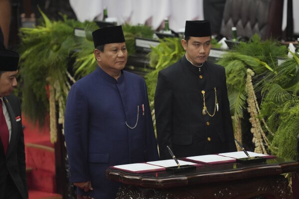 Indonesia's newly-inaugurated President Prabowo Subianto, left, and Vice President Gibran Rakabuming Raka prepare to sign their inauguration documents during their swearing in ceremony at the parliament building in Jakarta, Indonesia, Sunday, Oct. 20, 2024. (AP Photo/Tatan Syuflana)