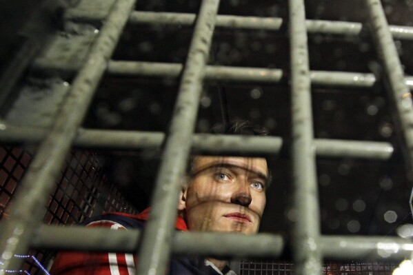 FILE - Alexei Navalny is seen behind the bars in the police van after he was detained during protests in Moscow, on May 8, 2012 a day after Putin's inauguration. Russia鈥檚 prison agency says that imprisoned opposition leader Alexei Navalny has died. He was 47. The Federal Prison Service said in a statement that Navalny felt unwell after a walk on Friday Feb. 16, 2024 and lost consciousness. (AP Photo/Sergey Ponomarev, File)