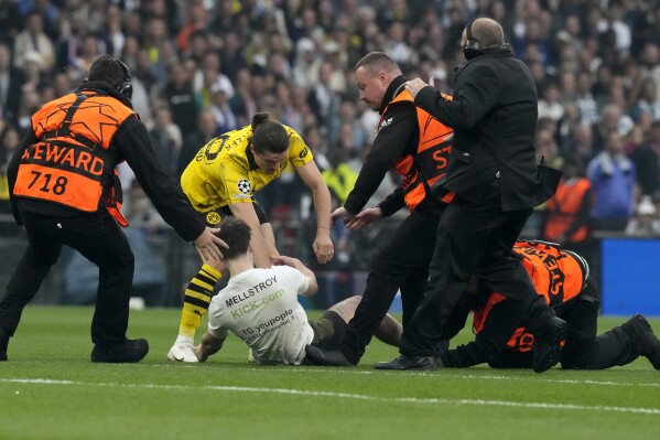 Dortmund's Marcel Sabitzer, center, and stewards chase a pitch invader during the Champions League final soccer match between Borussia Dortmund and Real Madrid at Wembley stadium in London, Saturday, June 1, 2024. (AP Photo/Frank Augstein)