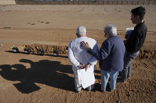 Volunteer chaplains pray during a graveside service at an indigent burial at the Maricopa County White Tanks Cemetery, Thursday, April 11, 2024, in Litchfield Park, Ariz. Many interred in Maricopa County's White Tanks Cemetery, where the county's dead are laid to rest if they they have no known family, have been the victims of heat-related deaths. (AP Photo/Ross D. Franklin)