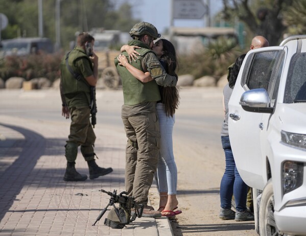 An Israeli soldier kisses his partner as she visits him near the border with the Gaza Strip, southern Israel, Friday, Oct. 20, 2023. (AP Photo/Ohad Zwigenberg)