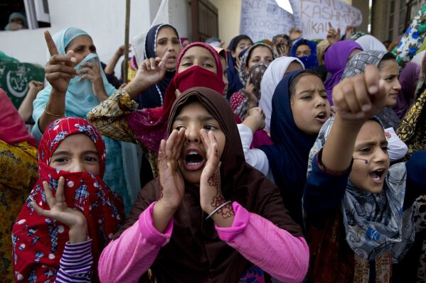 FILE- In this Sept. 27, 2019 file photo, Kashmiri girls shout freedom slogans during a protest after Indian government scrapped the region's semi-autonomy and imposed an unprecedented security clampdown in Srinagar, Indian controlled Kashmir. India’s Prime Minister Narendra Modi will attend a groundbreaking ceremony next month for a Hindu temple on a disputed site in northern India where a 16th-century mosque was torn down by Hindu hard-liners in 1992. The trust overseeing the temple construction says the ceremony is set for Aug. 5, a date they say is astrologically auspicious for Hindus but that also marks a year since the Indian Parliament revoked the semi-autonomous status of its only Muslim-majority state, Jammu and Kashmir.  (AP Photo/Dar Yasin, File)
