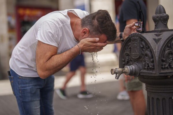 FILE - A man cool off in a fountain during a hot and sunny day of summer in Madrid, Spain, July 19, 2023. Human-caused global warming made July hotter for four out of five people on Earth, according to a new report issued Wednesday, Aug. 2, 2023, by Climate Central. (AP Photo/Manu Fernandez, File)