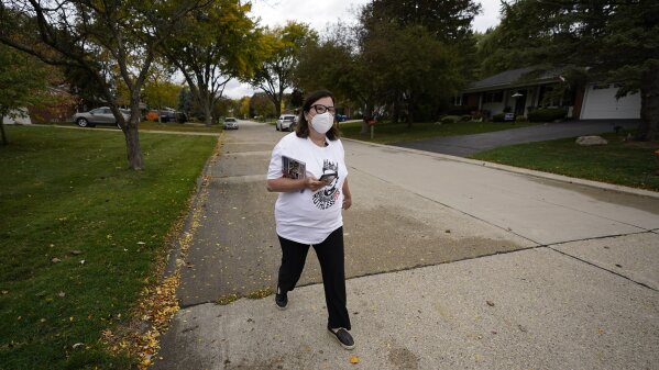 Lori Goldman walks between houses as she canvasses in Troy, Mich., Thursday, Oct. 15, 2020. Her Fems for Dems group has about 8,900 members. (AP Photo/Paul Sancya)