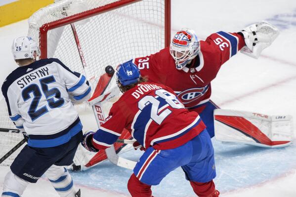 Montreal Canadiens goaltender Sam Montembeault stops Winnipeg Jets' Paul Stastny (25) as Canadiens' Christian Dvorak defends during the second period of an NHL hockey game, in Montreal, Monday, April 11, 2022. (Graham Hughes/The Canadian Press via AP)
