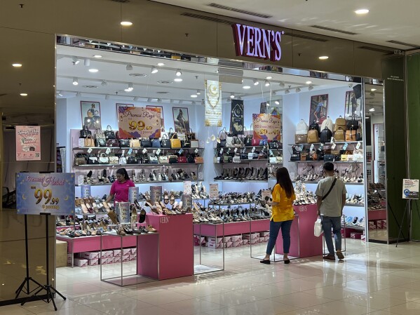 People shop at a Vern's outlet at a shopping mall in Kuala Lumpur, Malaysia, Monday, April 8, 2024. Vern’s Holdings, a Malaysian shoe company has apologized and stopped selling some of its footwear after some Muslims said the logo resembled the Arabic writing for the word God. (AP Photo/Vincent Thian)