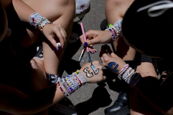 Fans of Taylor Swift paint their hands with the number 13 as they wait for the doors of Monumental stadium to open for her Eras Tour concert in Buenos Aires, Argentina, Thursday, Nov. 9, 2023. (AP Photo/Natacha Pisarenko)