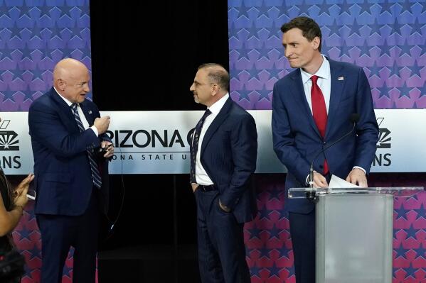 Arizona Democratic Sen. Mark Kelly, left, talks with Libertarian candidate Marc Victor, middle, and Republican candidate Blake Masters, right, prior to a televised debate in Phoenix, Thursday, Oct. 6, 2022. (AP Photo/Ross D. Franklin)