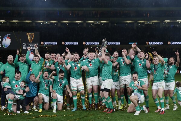 The Irish team celebrate as they pose for the cameras after lifting the Six Nations trophy after defeating Scotland in their rugby union international match at the Aviva stadium in Dublin, Ireland, Saturday, March 16, 2024. Ireland are the Six Nations champions. (AP Photo/Peter Morrison)