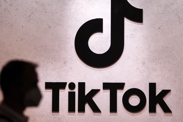 FILE - A visitor passes the TikTok exhibition stand at the Gamescom computer gaming fair in Cologne, Germany, Aug. 25, 2022. The same day Elon Musk abruptly dropped Twitter’s name and bird logo as part of its supposed transition to an “anything app” called X, TikTok impishly announced, late Monday, July 24, 2023, it will begin letting its users post text-based messages. (AP Photo/Martin Meissner, File)
