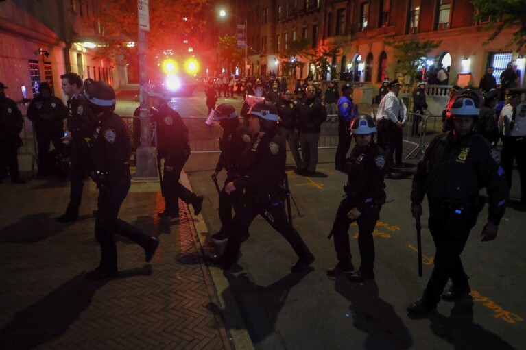 Miembros del Equipo de Respuesta Estratégica del Departamento de Policía de Nueva York avanzan hacia la entrada de la Universidad de Columbia, el martes 30 de abril de 2024, en Nueva York.  Después de ingresar al campus, un grupo de policías se acercó a Hamilton Hall, el edificio administrativo que los estudiantes manifestantes habían comenzado a ocupar ese mismo día.  (Foto AP/Julius Modell)