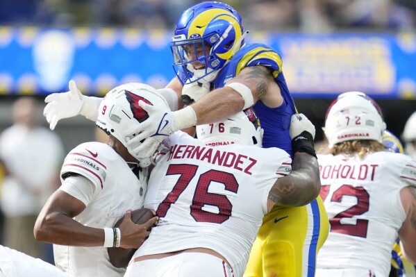 Los Angeles Rams linebacker Michael Hoecht (97), right, reaches to try to tackle Arizona Cardinals quarterback Joshua Dobbs (9) during the first half of an NFL football game Sunday, Oct. 15, 2023, in Inglewood, Calif. (AP Photo/Ashley Landis)