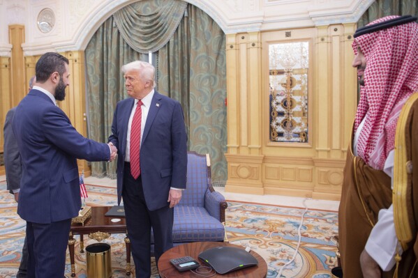 In this photo released by the Saudi Royal Palace, interim Syrian President Ahmad al-Sharaa shakes hands with U.S. President Donald Trump in Riyadh, Saudi Arabia, Wednesday, May 14, 2025. At right is Saudi Crown Prince Mohammed bin Salman. (Bandar Aljaloud/Saudi Royal Palace via AP)