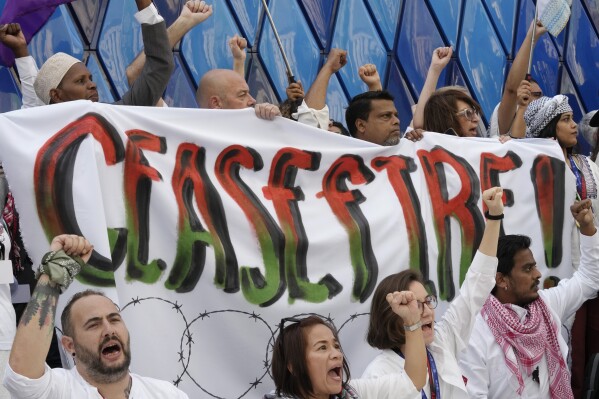 Pro-Palestinian demonstrators participating in a protest against the Israel-Hamas war hold a sign at the COP28 U.N. Climate Summit, Sunday, Dec. 3, 2023, in Dubai, United Arab Emirates. (AP Photo/Peter Dejong)