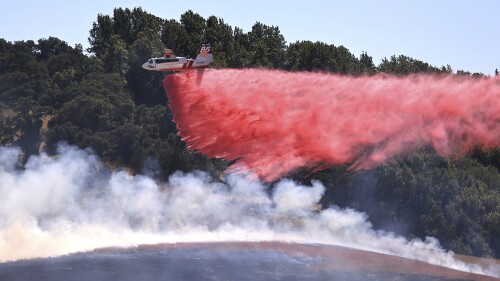 A pilot maneuvers Cal Fire 85 tanker from Sonoma Air Force Base to make a drop on the right flank of the San Antonio Fire, west of Petaluma, Calif., Friday, June 30, 2023. California is is in the midst of a heat wave over the long Fourth of July weekend.  (Kent Porter/The Press Democrat via AP)
