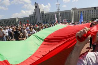 FILE - Supporters of Belarusian President Alexander Lukashenko hold a huge Belarusian State flag during a rally at Independent Square of Minsk, Belarus, Aug. 16, 2020. Cybersecurity experts say they have evidence of direct involvement by Belarus' government in a hybrid hacking/disinformation campaign against eastern European NATO members since 2016. The campaign has aimed to sow discord in the military alliance, steal confidential information and spy on dissidents. (AP Photo/Sergei Grits, File )