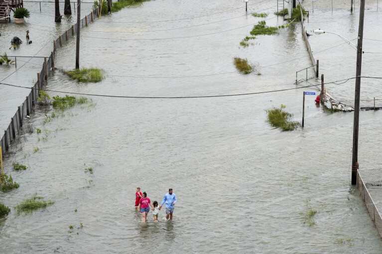 Members of the Vise family walk through the storm surge from Tropical Storm Alberto, Wednesday, June 19, 2024, in Surfside Beach, Texas. They said they needed to get out of their house. ( Jon Shapley/Houston Chronicle via AP)