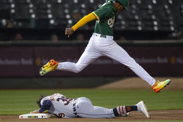 Oakland Athletics starting pitcher Luis Medina jumps over Detroit Tigers' Zach McKinstry (39), who slides into third base after hitting a double and advancing on an error during the fifth inning of a baseball game Thursday, Sept. 21, 2023, in Oakland, Calif. (AP Photo/D. Ross Cameron)