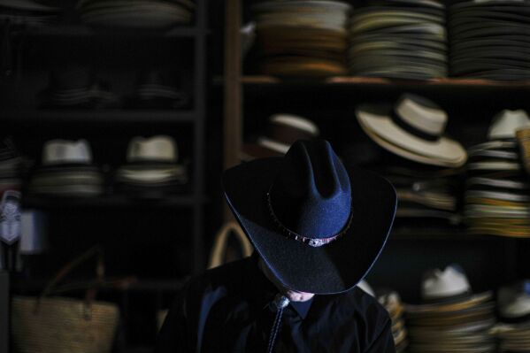 A customer tries on a hat at the “Donde Golpea el Monito” hat shop and museum that preserves a hat-making tradition dating back to 1915, in Santiago, Chile, Thursday, April 3, 2025. (AP Photo/Esteban Felix)