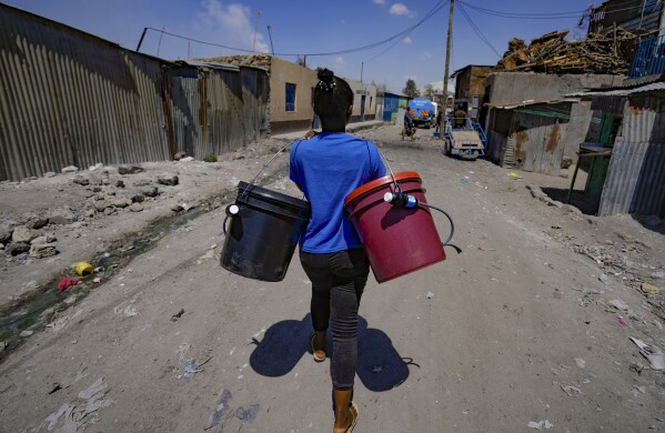 A woman walks to fetch water with a bucket filter in Athi River, Machakos county, Kenya, Tuesday, Oct. 17, 2023. The devices are the size of a small water bottle and are fitted with a hose pipe onto a bucket. They can filter water from the river and nearby swamps into potable water that can be used by residents. (AP Photo/Brian Inganga)