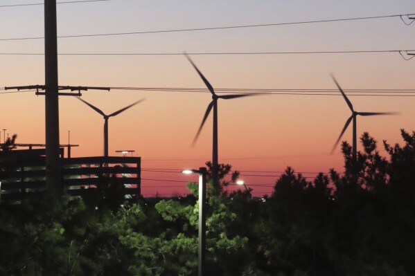 The sun sets behind spinning land-based wind turbines in Atlantic City, N.J., on Dec. 13, 2023. On April 24, 2024, eight Jersey Shore towns wrote to New Jersey utility regulators saying that a proposed wind farm off Long Beach Island will be costlier than expected. (AP Photo/Wayne Parry)