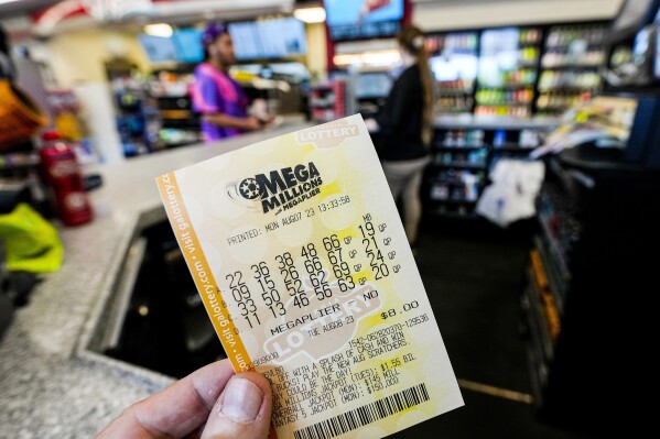 FILE - A Mega Millions ticket is seen as a person makes a purchase inside a convenience store, Aug. 7, 2023, in Kennesaw, Ga. The winning numbers for a nearly $1 billion Mega Millions lottery prize will be drawn Friday night, March 22, 2024, offering the hope of sudden riches for a lucky player and almost certain disappoint for everyone else. (AP Photo/Mike Stewart, File)