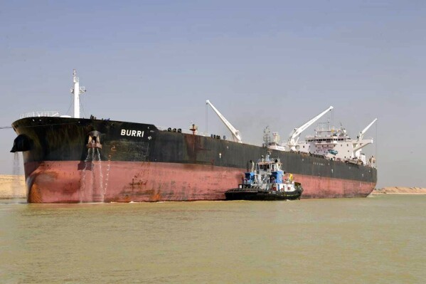 In this handout photo released by the Suez Canal Authority on August 23, 2023, a ship, The Burri, and a tugboat are shown in the waterway after a collision with another large transport vessel. Egyptian authorities said two tankers have collided in the Suez Canal, disrupting traffic through the global waterway. The Suez Canal authority says the BW Lesmes, a Singapore-flagged tanker that carries liquefied natural gas, suffered a mechanical malfunction and ran aground while transiting through the canal. The Burri, a Cayman Island-flagged tanker which carries oil products, collided with the broken vessel. (Suez Canal Authority via AP)