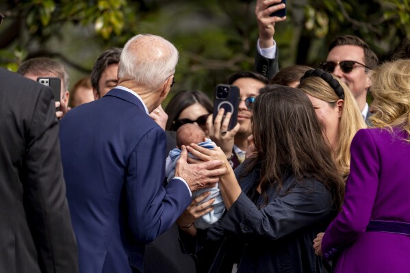 President Joe Biden, left, accompanied by first lady Jill Biden, far right, holds a baby as they greet guests on the South Lawn before boarding Marine One at the White House in Washington, Friday, March 8, 2024, for a short trip to Andrews Air Force Base, Md., and then on to Philadelphia for a campaign event. (AP Photo/Andrew Harnik)