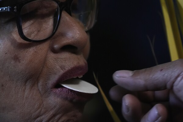A person receives communion during a Palm Sunday Passion Play at the San Lucas de Iztapalapa parish in Mexico City, Sunday, April 13, 2025. (AP Photo/Marco Ugarte)
