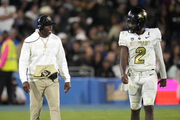 Colorado head coach Deion Sanders, left, talks to his son quarterback Shedeur Sanders during the second half of an NCAA college football game against UCLA Saturday, Oct. 28, 2023, in Pasadena, Calif. (AP Photo/Mark J. Terrill)