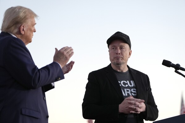 Republican presidential nominee former President Donald Trump, left, claps as Tesla and SpaceX CEO Elon Musk prepares to depart after speaking at a campaign event at the Butler Farm Show, on Oct. 5, 2024, in Butler, Pa. (AP Photo/Alex Brandon, File)