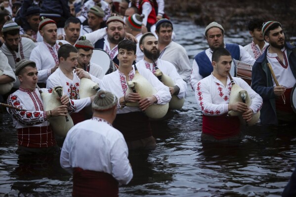 Men play bagpipes and drums as they wade into the cold Tundzha River to celebrate Epiphany, in the town of Kalofer, Bulgaria, Saturday, Jan. 6, 2024. The legend goes that the person who retrieves the wooden cross from the river will be freed from evil spirits and will be healthy throughout the year. Epiphany marks the end of the 12 days of Christmas, but not all Orthodox Christian churches celebrate it on the same day. (AP Photo/Valentina Petrova)