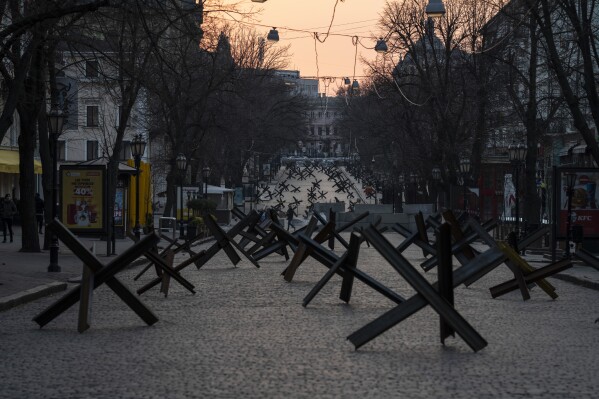 A woman walks through anti- tank barricades placed on a street as preparation for a possible Russian offensive, in Odesa, on Thursday March 24, 2022. (AP Photo/Petros Giannakouris)
