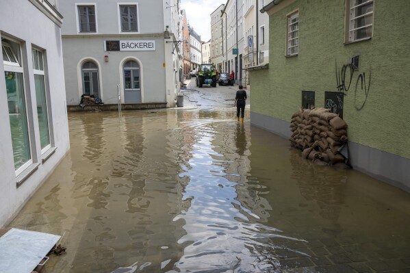 A woman walks through a flooded alley in the city on the three rivers, Passau, Germany, Wednesday June 5, 2024. Many places in Bavaria continue to be flooded after heavy rainfall. (Peter Kneffel/dpa via AP)