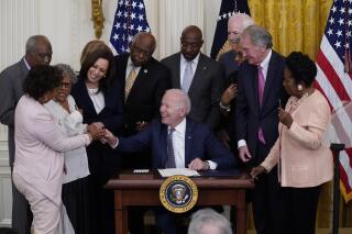 FILE - In this June 17, 2021, file photo, President Joe Biden hands a pen to Rep. Barbara Lee, D-Calif., after signing the Juneteenth National Independence Day Act, in the East Room of the White House in Washington. From left, Rep. Barbara Lee, D-Calif, Rep. Danny Davis, D-Ill., Opal Lee, Sen. Tina Smith, D-Minn., obscured, Vice President Kamala Harris, House Majority Whip James Clyburn of S.C., Sen. Raphael Warnock, D-Ga., Sen. John Cornyn, R-Texas, Rep. Joyce Beatty, D-Ohio, obscured, Sen. Ed Markey, D-Mass., and Rep. Sheila Jackson Lee, D-Texas. (AP Photo/Evan Vucci, File)