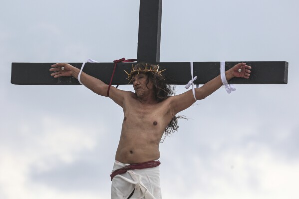 Ruben Enaje remains on the cross during the reenactment of Jesus Christ's sufferings as part of Good Friday rituals in San Pedro Cutud, north of Manila, Philippines, Friday, March 29, 2024. The Filipino villager was nailed to a wooden cross for the 35th time to reenact Jesus Christ’s suffering in a brutal Good Friday tradition he said he would devote to pray for peace in Ukraine, Gaza and the disputed South China Sea. (AP Photo/Gerard V. Carreon)