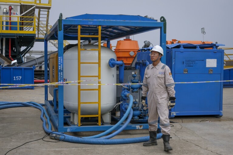 A Chinese worker from China Oilfield Services Limited (COSL), a contractor for China National Offshore Oil Corporation (CNOOC), stands by machinery next to the drilling rig at the Kingfisher oil field on the shores of Lake Albert in the Kikuube district of western Uganda, Jan. 24, 2023. (AP Photo/Hajarah Nalwadda)