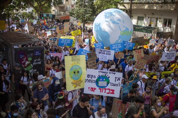 People holding banners and a balloon of the globe march to demand the world leaders to take action in reversing climate change and stop the use of fossil fuels in Tel Aviv, Israel, Friday, Oct. 29, 2021. Thousands of Israelis gathered Friday in Tel Aviv to take part in a worldwide day of action before leaders head to the Scottish city of Glasgow for the start of the U.N. Climate Change Conference, known as COP26. (AP Photo/Ariel Schalit)