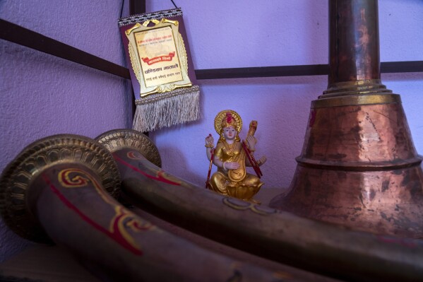 An idol of Saraswati, Hindu goddess of knowledge, is seen next to traditional musical instruments of the Naumati Baja, in a practice room in Kathmandu, Nepal, Tuesday, March 5, 2024. The naumati baja was once associated only with men from the Damai community, part of the lowest caste. Discrimination based on caste is believed to have caused some musicians to quit playing naumati baja. (AP Photo/Niranjan Shrestha)