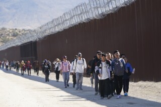 A group of people, including many from China, walk along the wall after crossing the border with Mexico to seek asylum, near Jacumba, Calif., Oct. 24, 2023. Ecuador on Tuesday, June 18, 2024, announced the suspension of an agreement with China that had waived visas for Chinese citizens traveling to the South American country, due to the increase in unusual migratory flows, using Ecuador as a starting point to reach other nations in the hemisphere through irregular routes, the Foreign Ministry said. (AP Photo/Gregory Bull, File)