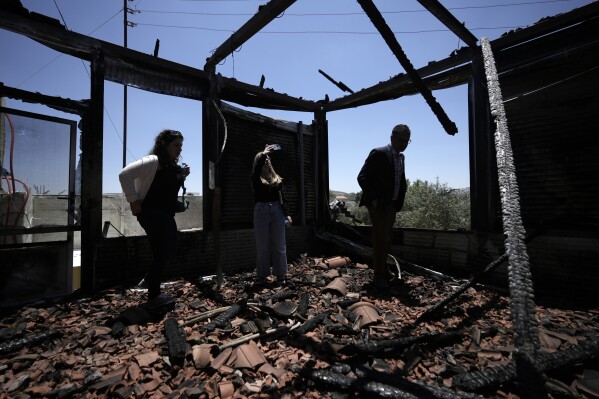 An international delegation examines a torched building as they tour the West Bank town of Turmus Ayya, days after a rampage by Jewish settlers, Friday, June 23, 2023. Israeli settlers entered the town, setting fire to Palestinian cars and homes after four Israelis were killed by Palestinian gunmen in the northern West Bank on Tuesday. (AP Photo/Majdi Mohammed)