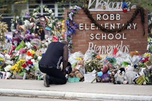FILE - Reggie Daniels pays his respects a memorial at Robb Elementary School, June 9, 2022, in Uvalde, Texas, created to honor the victims killed in the school shooting. Nearly two years after the deadly school shooting in Uvalde that left 19 children and two teachers dead, the city council will discuss Thursday, March 7, 2024, the results of an independent investigation it requested into the response by local police officers. (AP Photo/Eric Gay, File)