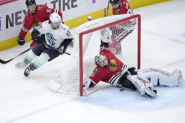 Chicago Blackhawks goaltender Alex Stalock, right, makes a save as Seattle Kraken's Brandon Tanev (13) looks for a rebound during the second period of an NHL hockey game Saturday, Jan. 14, 2023, in Chicago. (AP Photo/Charles Rex Arbogast)