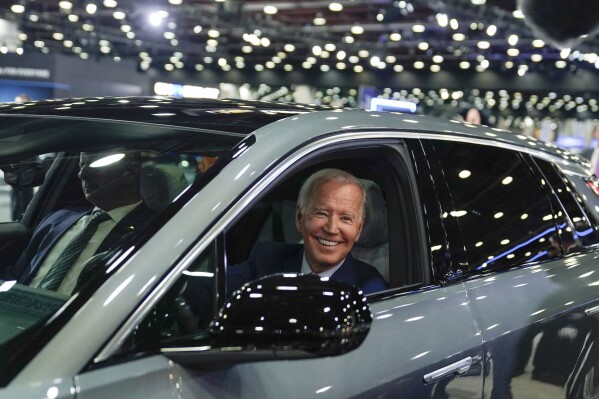 FILE - President Joe Biden drives a Cadillac Lyriq through the show room during a tour at the Detroit Auto Show, Sept. 14, 2022, in Detroit. Former President Donald Trump and other Republicans portray Biden's policy to promote electric vehicles as unfair for consumers and government overreach. Biden and Democrats have been less vocal and more nuanced, advocating Biden's climate reduction goals while promoting homegrown technology over competition from China. (AP Photo/Evan Vucci, File)