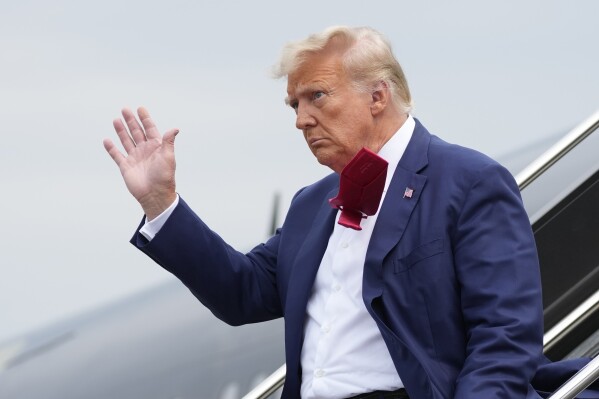 FILE - Former President Donald Trump waves as he steps off his plane at Ronald Reagan Washington National Airport, Aug. 3, 2023, in Arlington, Va. A slim majority of Americans approve of the U.S. Justice Department indicting Trump over his efforts to remain in office after losing the 2020 election, according to a new poll from The Associated Press-NORC Center for Public Affairs Research. (AP Photo/Alex Brandon, File)