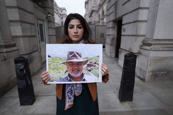 FILE - Roxanne Tahbaz holds a picture of her father Morad Tahbaz who is jailed in Iran, during a protest outside the Foreign, Commonwealth and Development Office in London, April 13, 2022. Iran has transferred five Iranian-Americans from prison, identifying three of the prisoners as Siamak Namazi, Emad Shargi, and Morad Tahbaz, to house arrest. The move comes after Tehran has spent months suggesting a prisoner swap with Washington. (Stefan Rousseau/PA via AP, File)