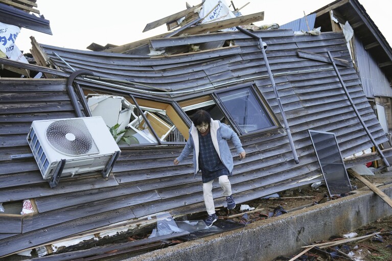 A resident checks her destroyed house in Wajima, Ishikawa prefecture, Japan Friday, Jan. 5, 2024. Monday’s temblor decimated houses, twisted and scarred roads and scattered boats like toys in the waters, and prompted tsunami warnings. (Kyodo News via AP)